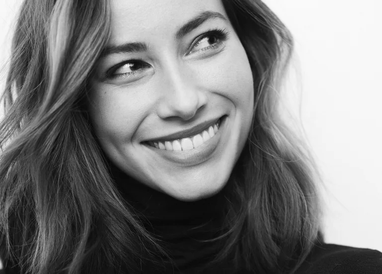 Smiling woman with wavy hair, showing her bright teeth in a joyful expression